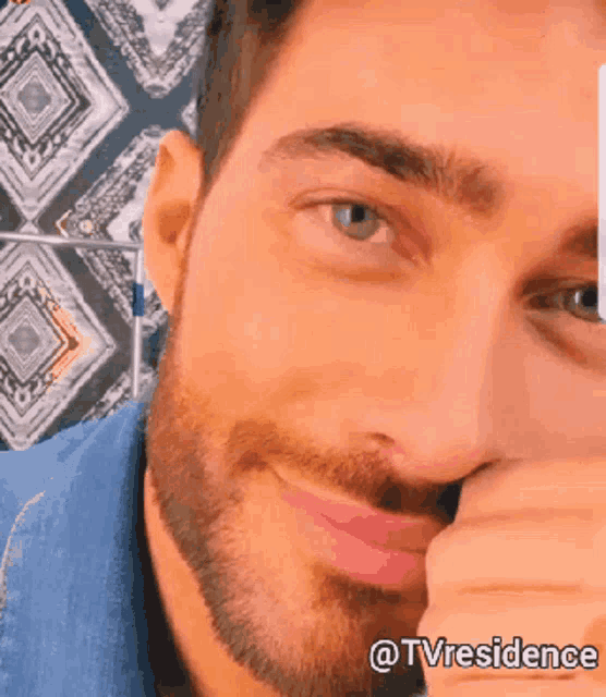 a man with a beard is smiling and covering his mouth with his hand with the words tvresidence below him