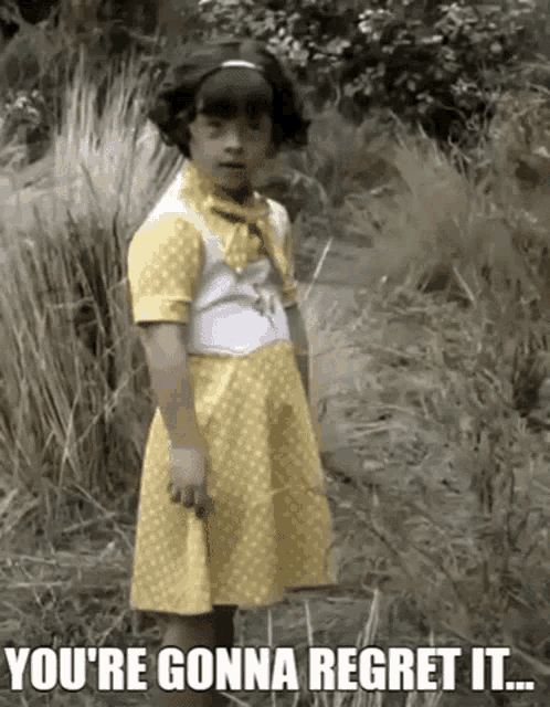 a little girl in a yellow dress is standing in the grass with the words you 're gonna regret it ..