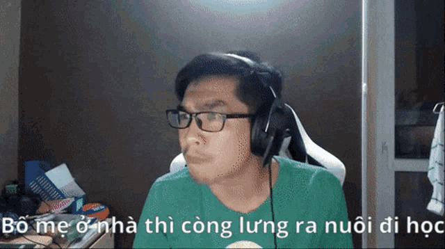 a man wearing headphones and a green shirt says bo me o nha thi cong lung ra nuoi di hoc