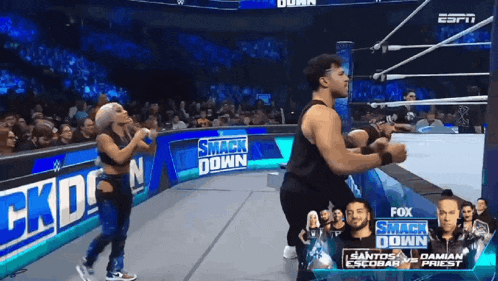 a man and a woman are dancing in a wrestling ring with a sign that says smack down