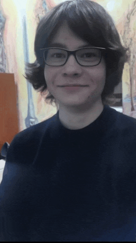 a young man wearing glasses and a black shirt smiles at the camera