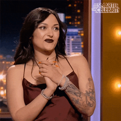 a woman with a tattoo on her arm is sitting on a stage with the words " smarter than celebrity " behind her