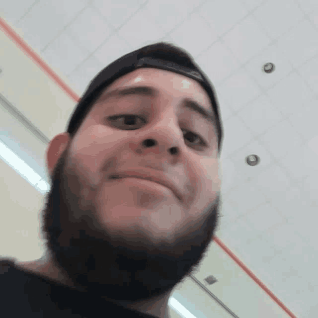 a man with a beard wearing a black hat is smiling