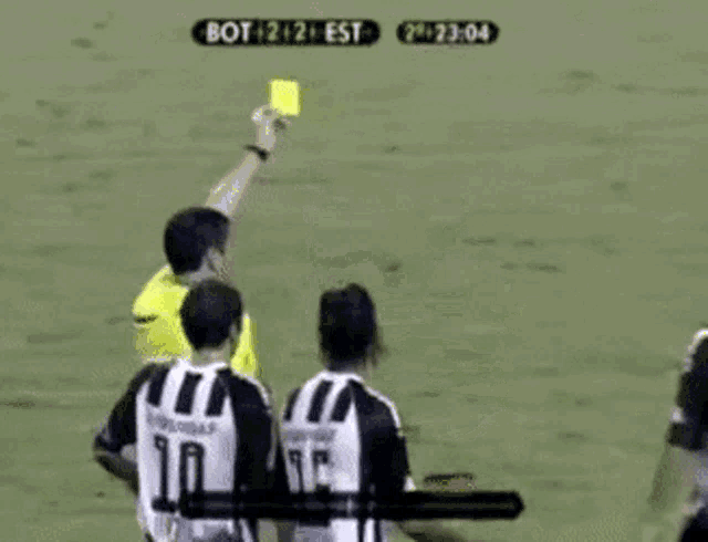a referee is giving a yellow card to a soccer player with the number 10 on the back of his jersey