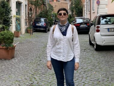 a woman stands on a cobblestone street in Italy.