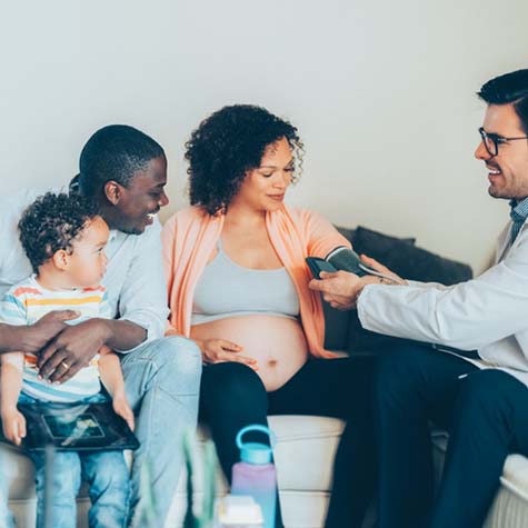 Doctor visiting pregnant woman at home with her family