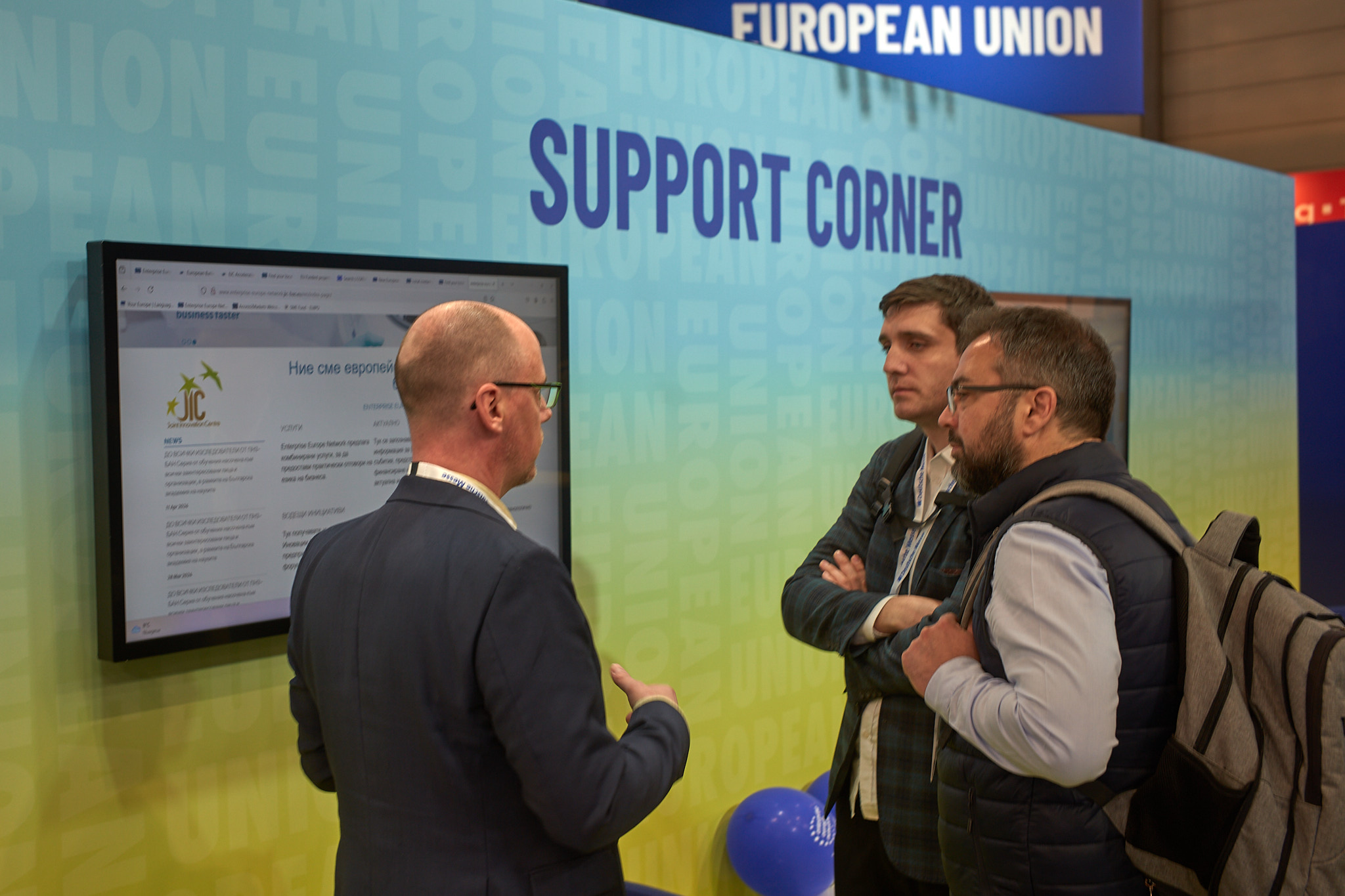 People talking in front of the European Commission's stand support corner