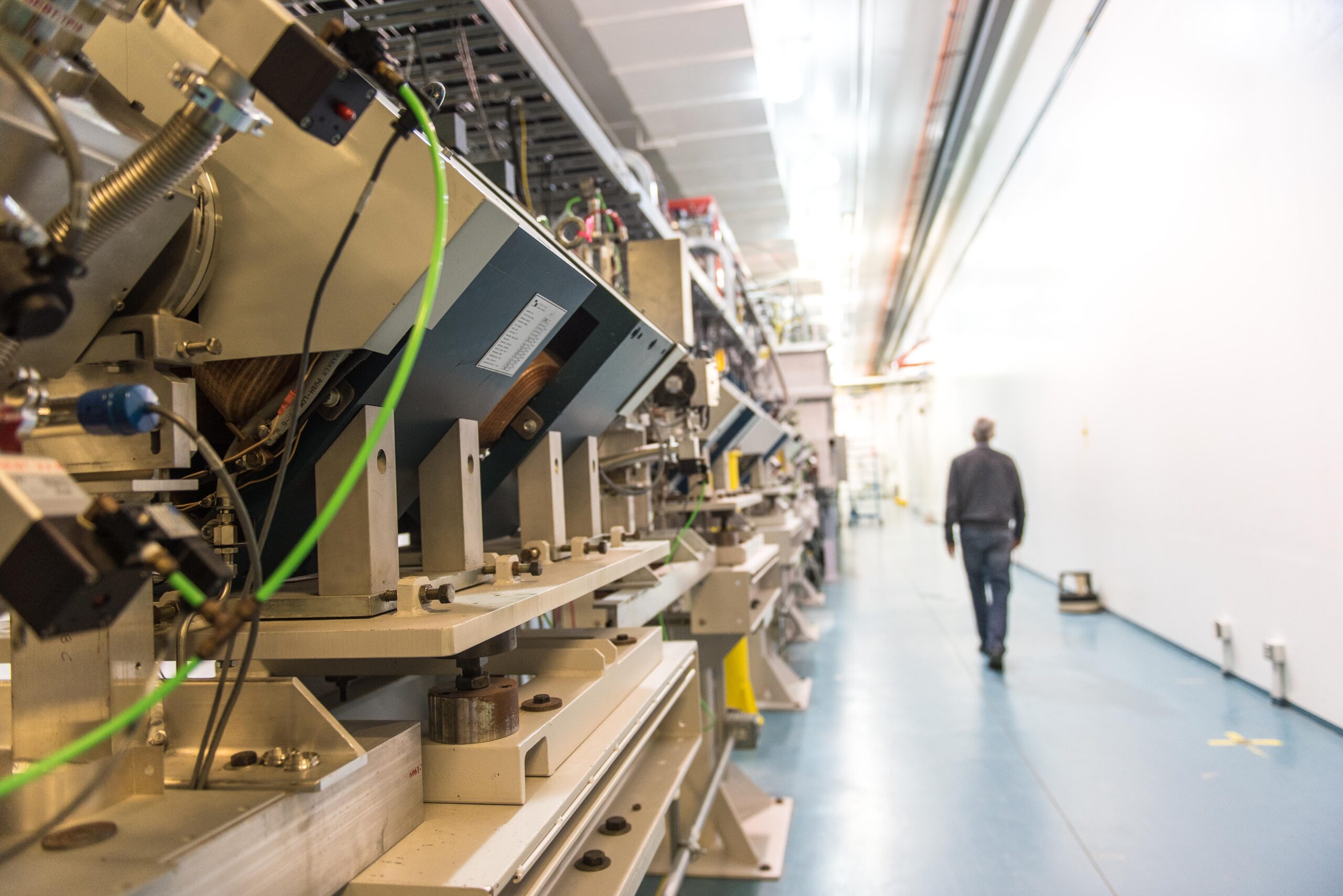 person walking down a long corridor which has a beamline running through it