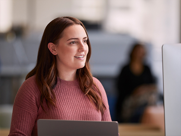 MacBook’unda çalışırken yana doğru bakan bir Apple Yazılım ve Hizmetler çalışanı.