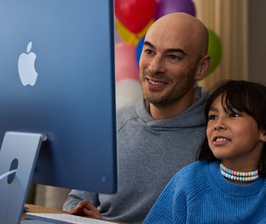 Bir yetişkin ve bir çocuk birlikte mavi bir iMac kullanıyor