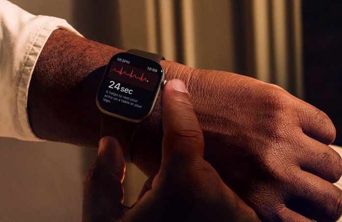Une personne appuie sur la Digital Crown d’une Apple Watch Series 11 en maintenant la pression pour mesurer sa santé cardiaque dans l’app ECG