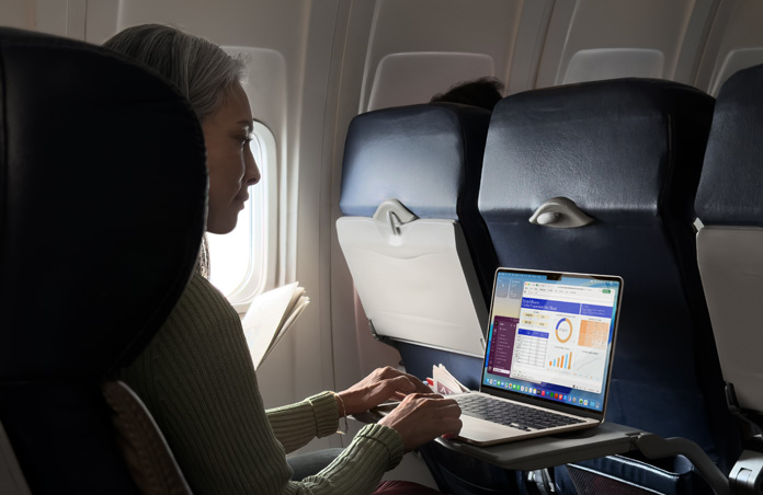 Una persona sentada en un avión trabaja en su MacBook Air