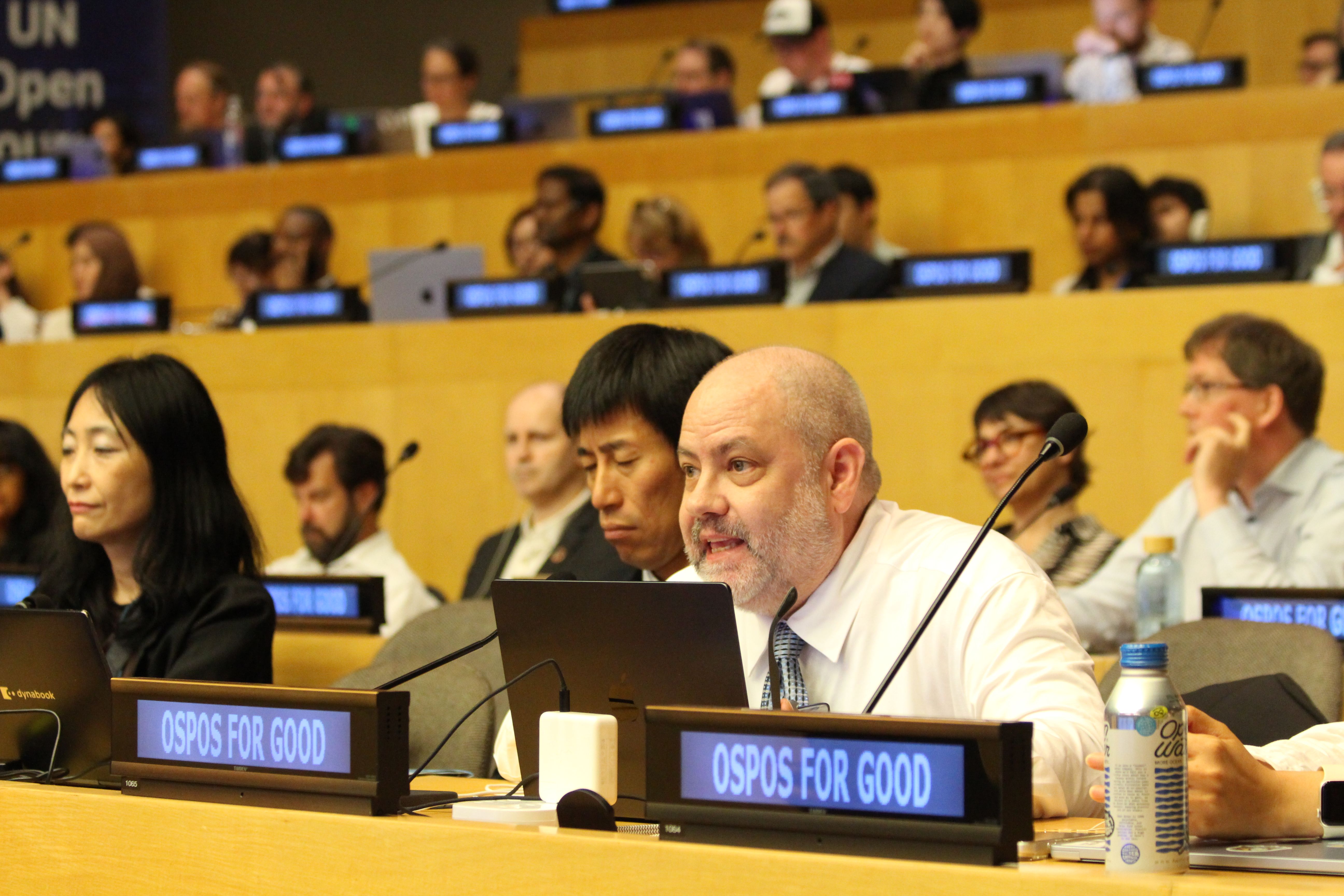 Matthew Saunders in a dress shirt and tie speaking a the UN.
