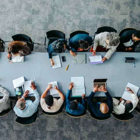 People seated around a meeting table illustrating new management leadership.