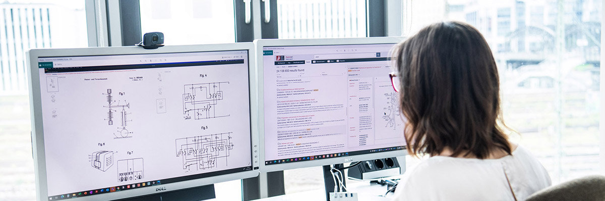 An examiner works in front of 2 computer screens