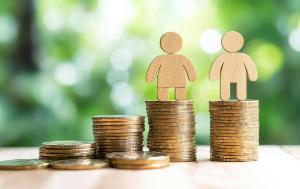 A few piles of coins on a table and two small figures on them representing different genders