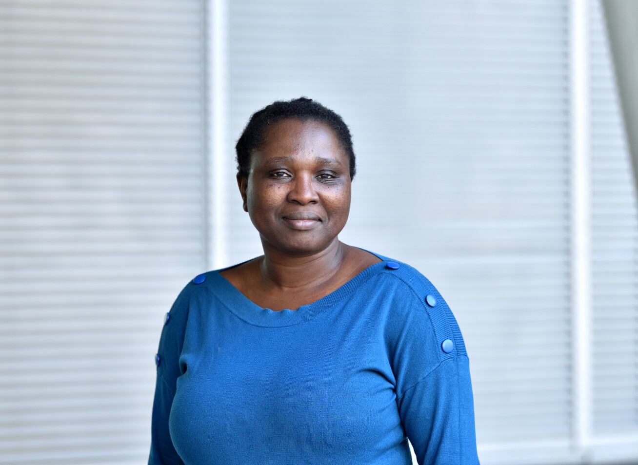 Elizabeth Olanloye wearing blue top and smiling at the camera