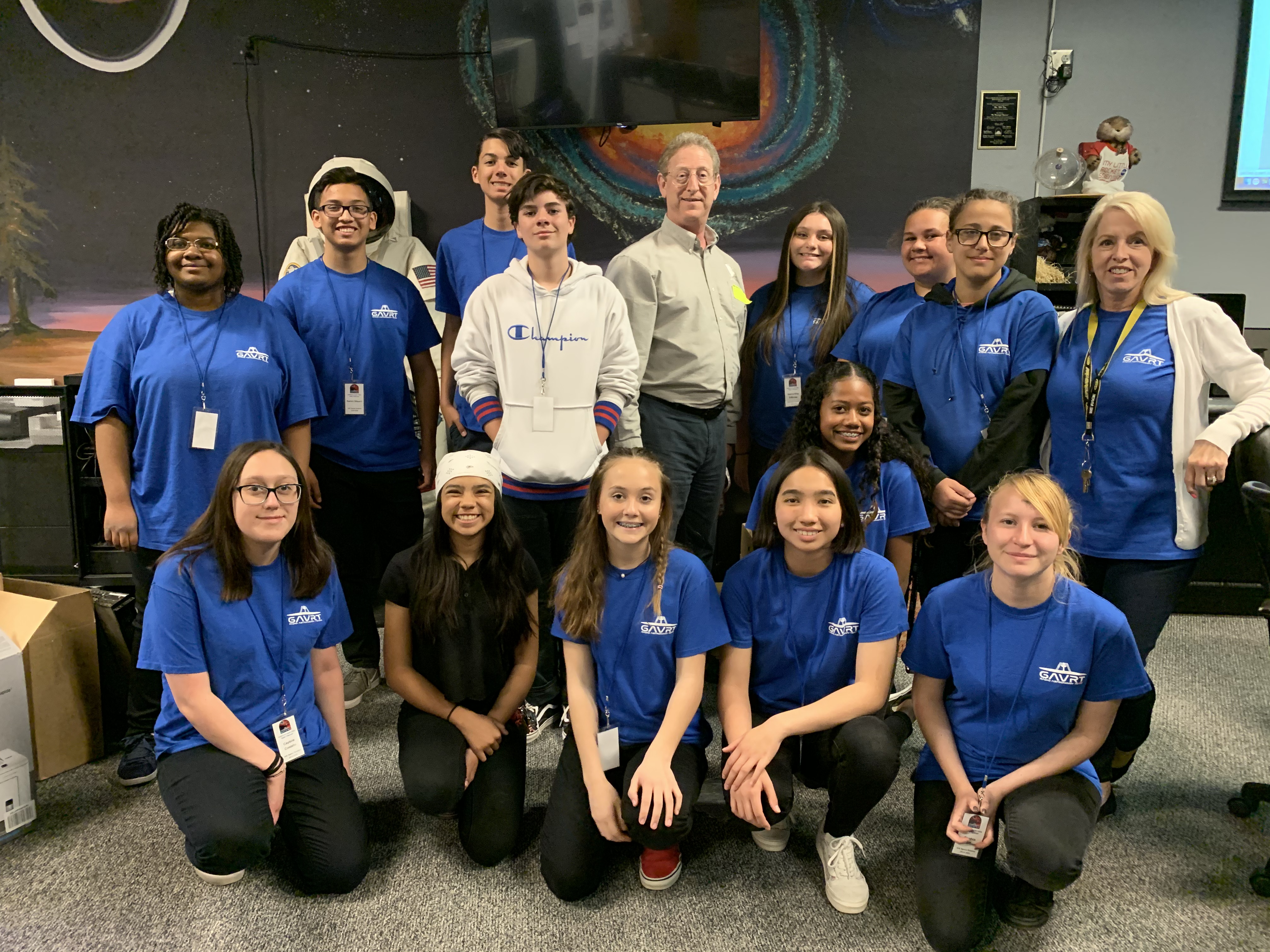 A group of students stand and kneel smiling with Dr. Steven Levin.