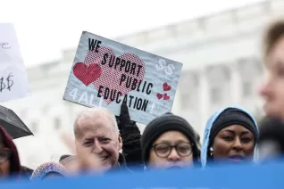 A crowd of people holding various signs about supporting public education.