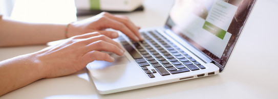 Arbeit am Laptop Studentin tippend am Laptop, daneben liegen Bücher.