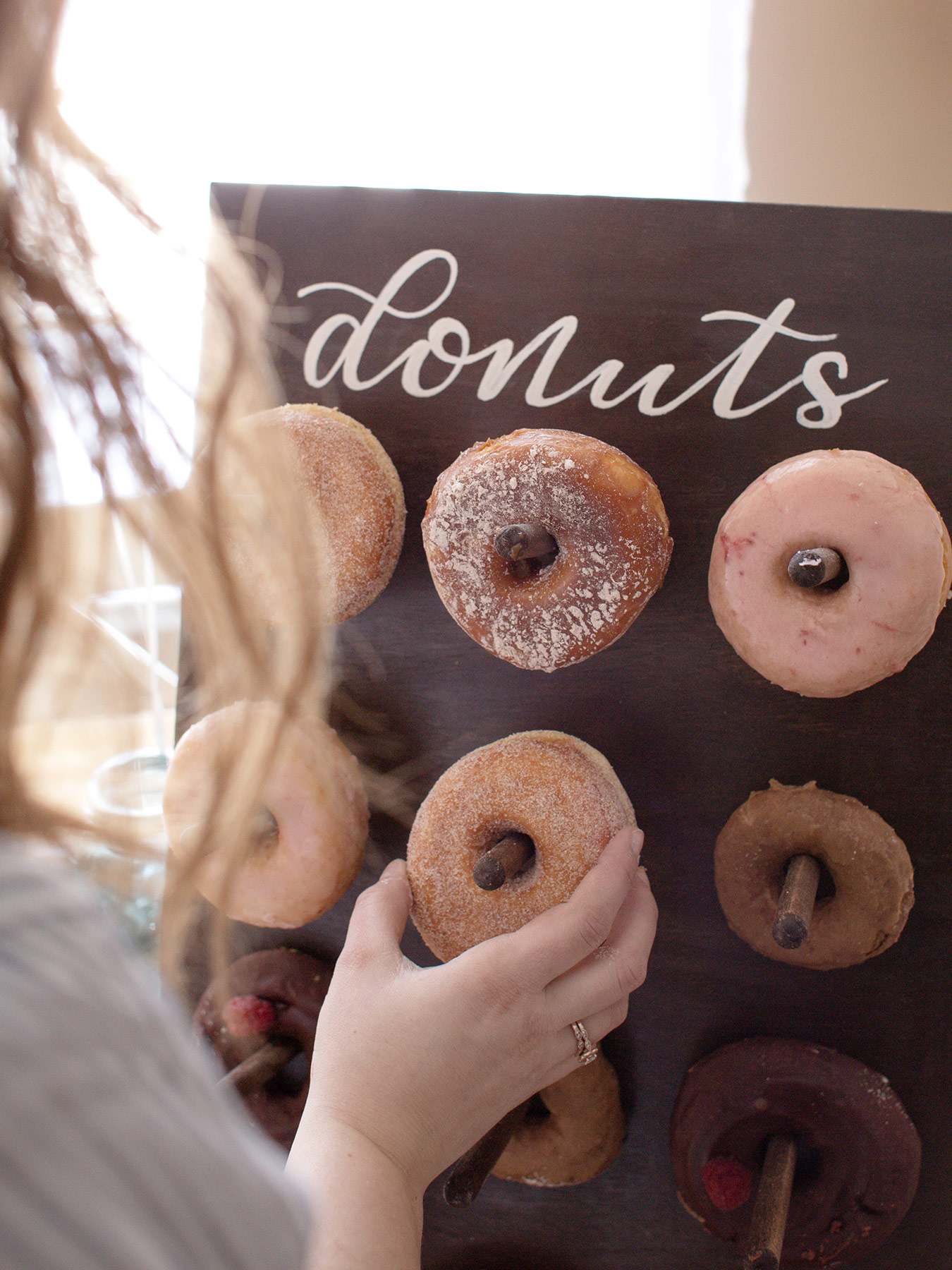 A person taking a donut from a donut wall display.
